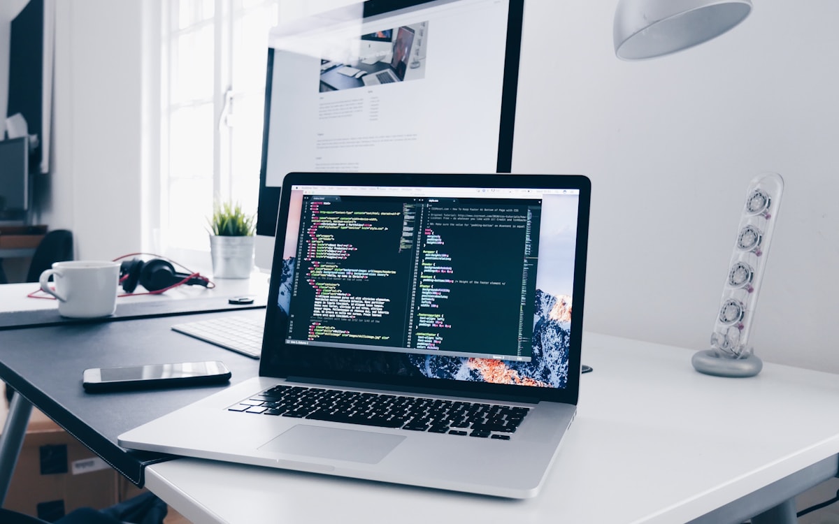 A blog photo of a desk workspace with a laptop, keyboard and desk accessories